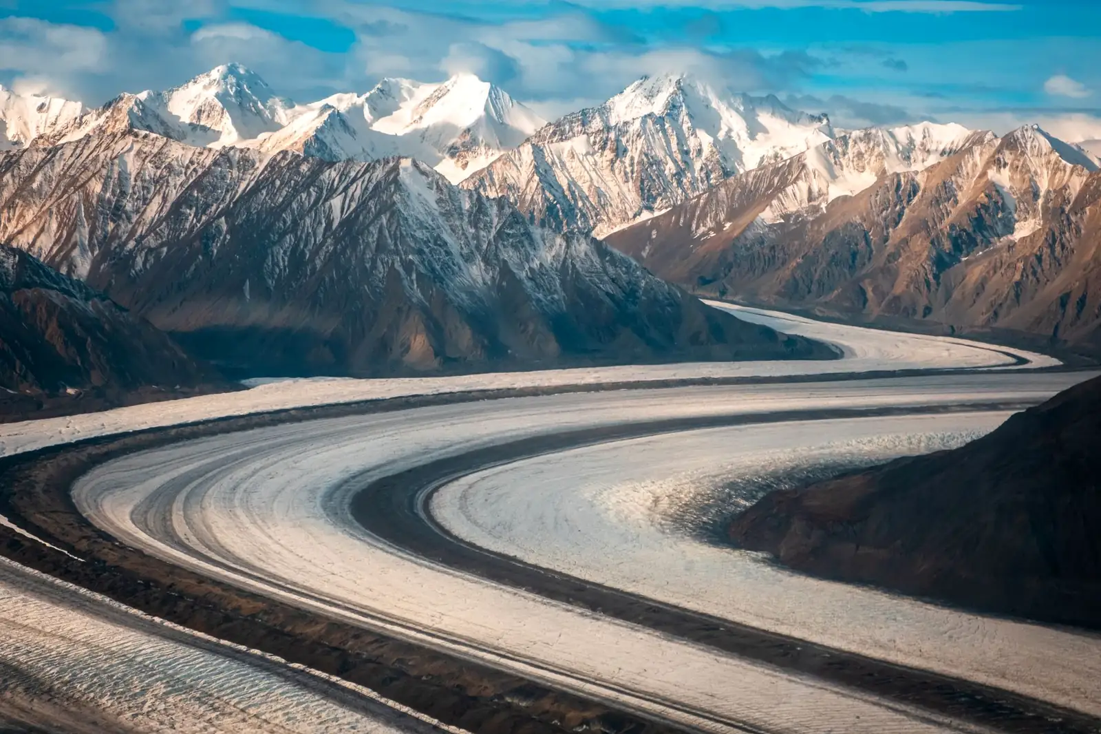 Aerial view of a curving glacier winding between snow-capped peaks near Haines Junction, Yukon