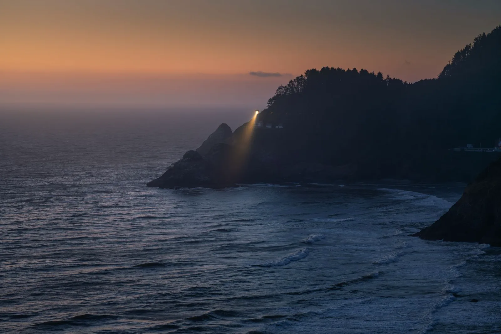 Heceta Head Lighthouse casting its beam over the Pacific at dusk on the central Oregon coast